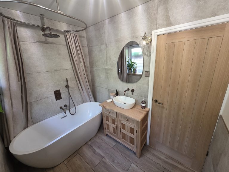 Bathroom refit by Phix Pro with freestanding bath, wood vanity unit and oak door