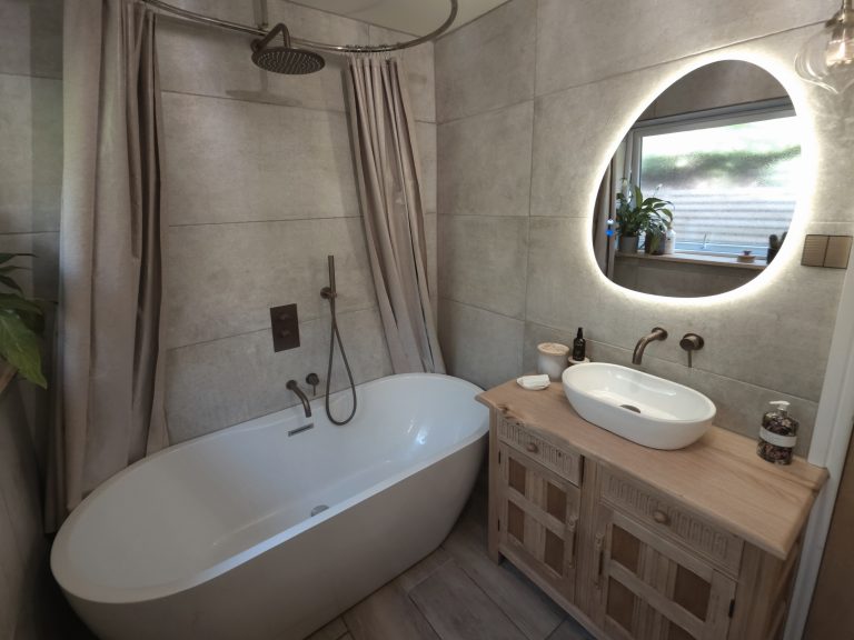 Freestanding bath and illuminated oval mirror in a bathroom finished by Phix Pro